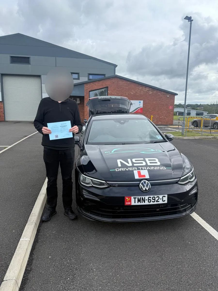 An anonymised learner holding a pass certificate beside the NSB Driver Training car